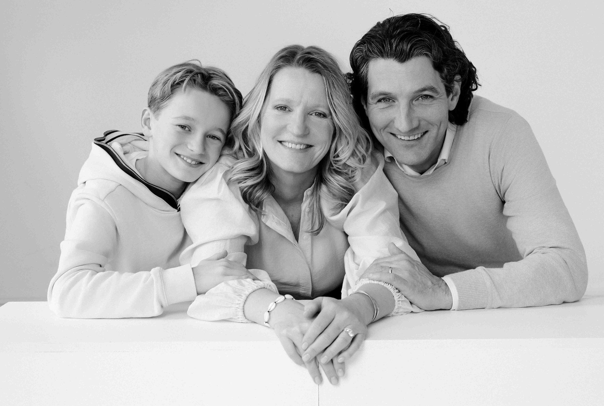 A family of three resting close, hands gently clasped.
