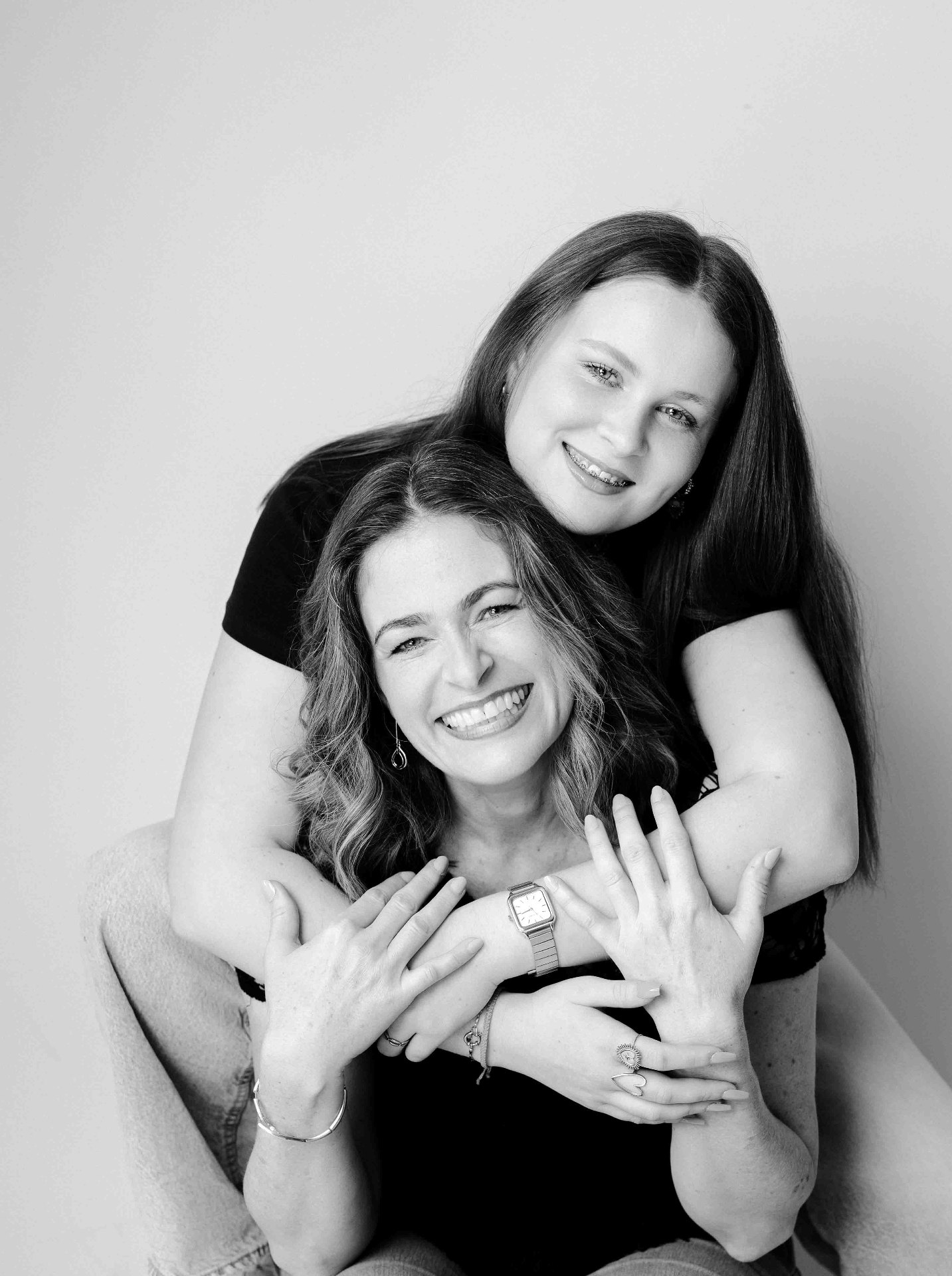 A teenage daughter wrapped around her mother, both beaming.