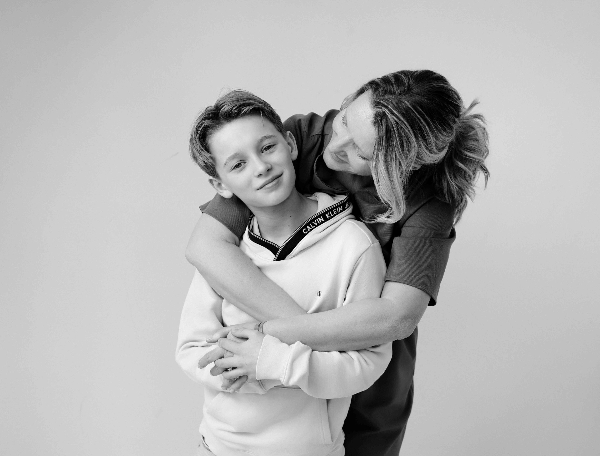 A mother embracing her young son in soft natural light.