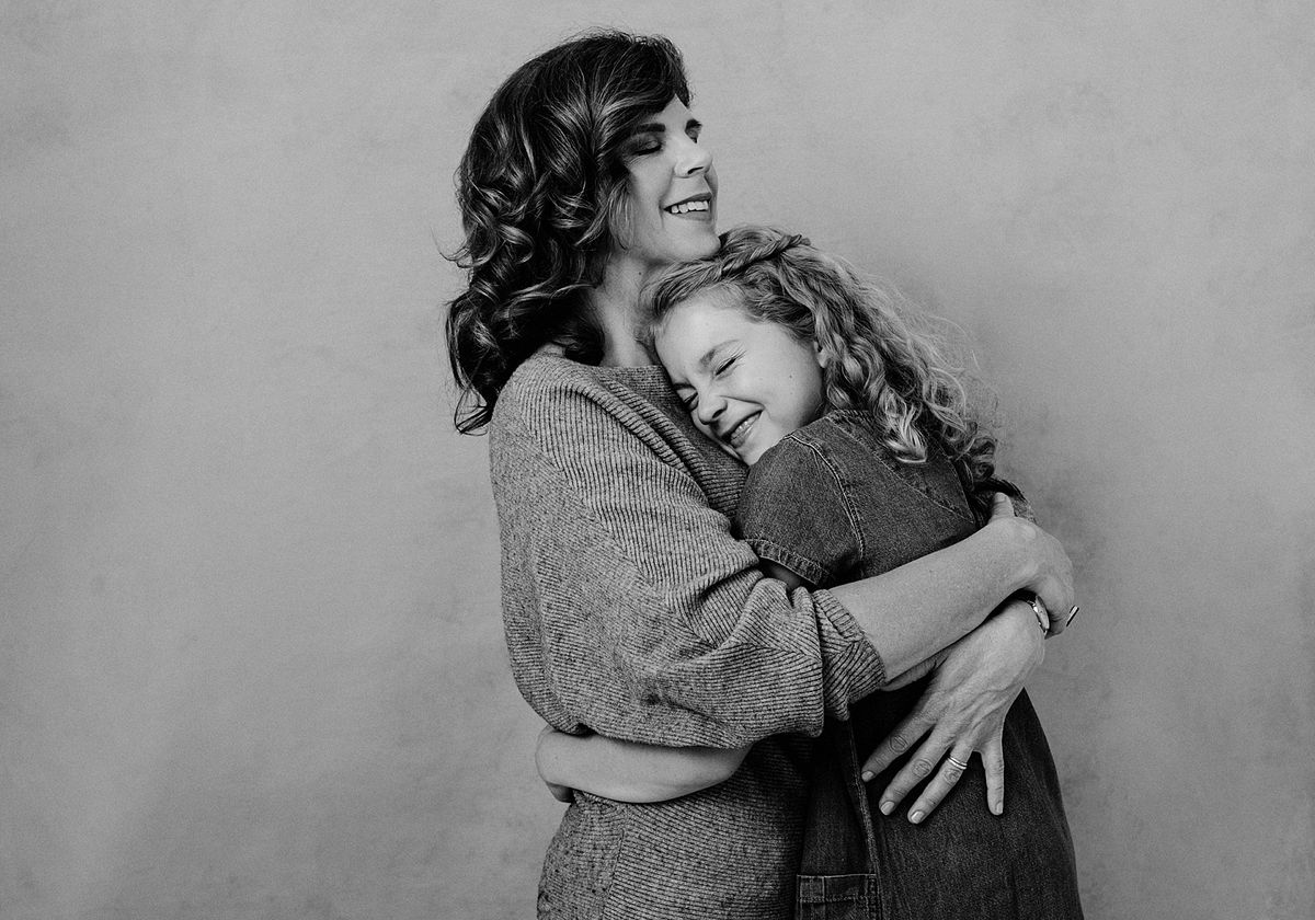 A family laughing softly together in warm studio light.